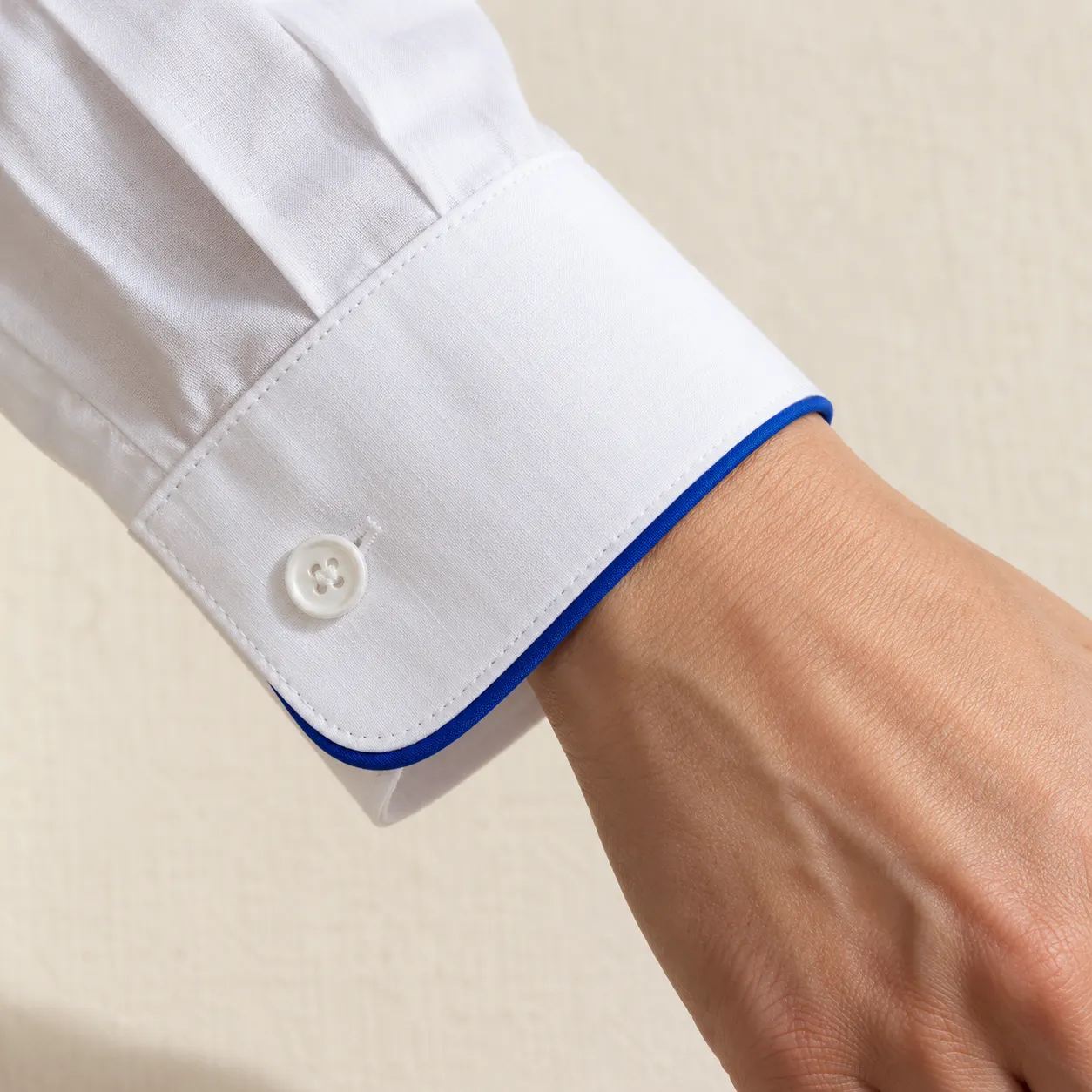 Puño de camisa blanca con un vivo azul intenso cosido en el borde